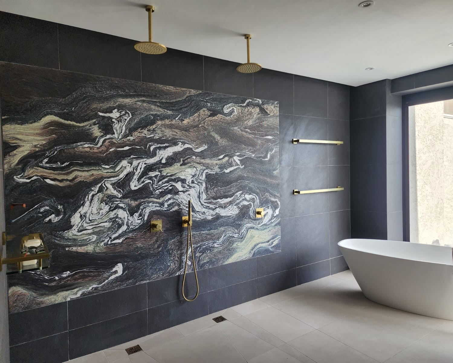 Double rain shower with marble feature wall and freestanding bath