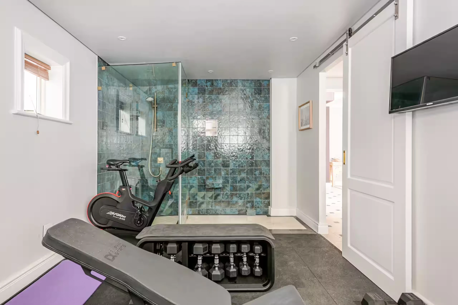 Private gym and steam room with weights, bike, shower and bench
