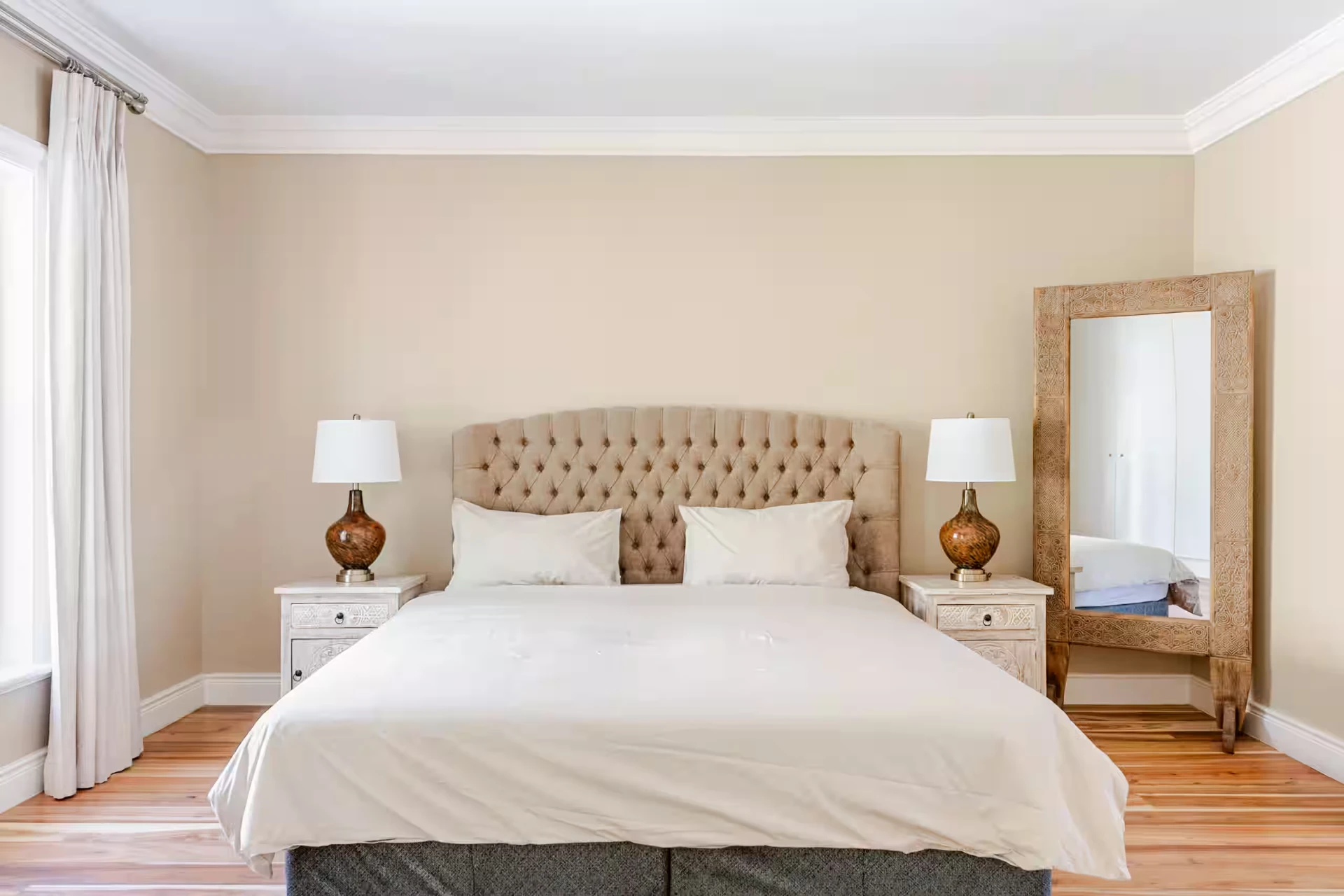 Second bedroom with buttoned headboard, carved mirror and acacia wood floors